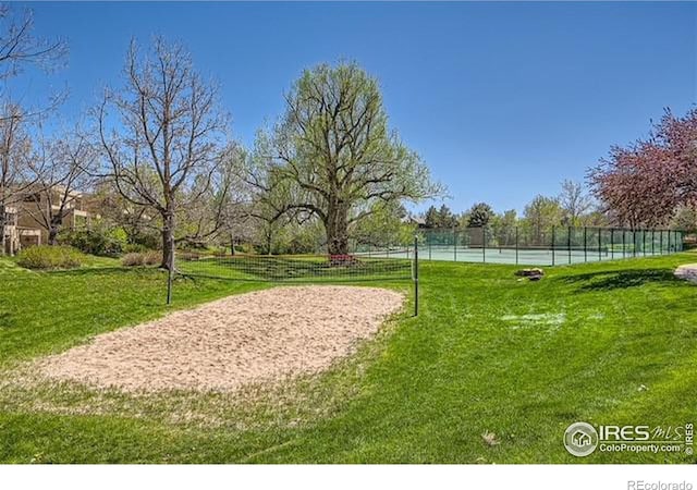 surrounding community with tennis court, a lawn, and volleyball court