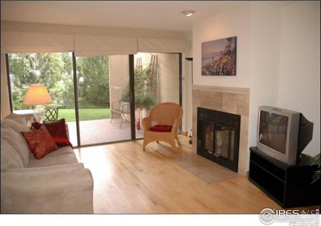 living room with a tiled fireplace and hardwood / wood-style floors