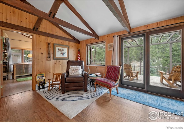 sitting room with hardwood / wood-style flooring, a baseboard radiator, vaulted ceiling with beams, and wooden walls