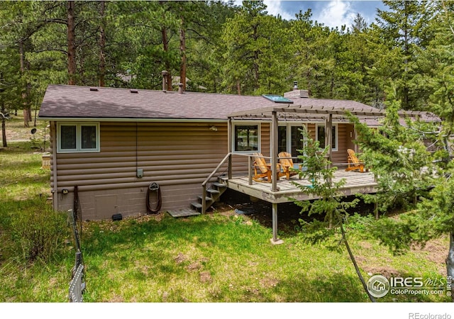 back of property with a yard, a pergola, and a deck