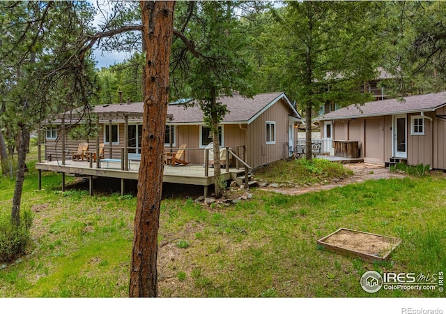 back of house featuring a wooden deck and a lawn