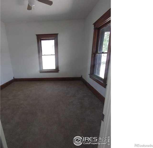 unfurnished room with ceiling fan and dark colored carpet