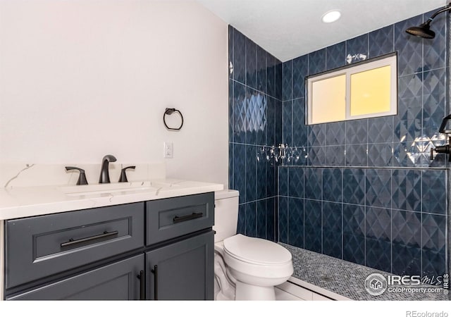 bathroom featuring vanity, toilet, and a tile shower