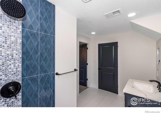 bathroom featuring tile patterned flooring, vanity, lofted ceiling, and a textured ceiling