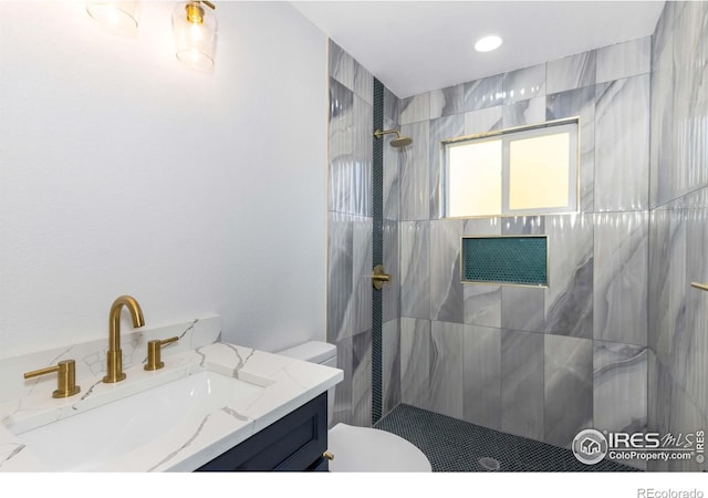 bathroom featuring vanity, a tile shower, and toilet