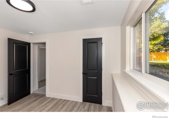 unfurnished bedroom featuring a textured ceiling and light hardwood / wood-style flooring