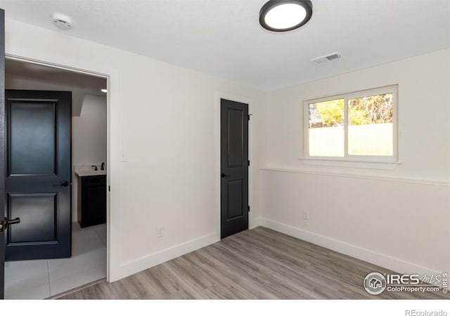 unfurnished room featuring sink and light hardwood / wood-style floors