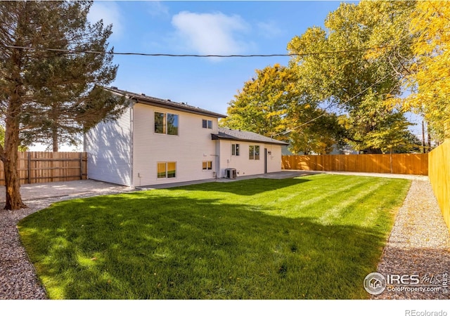 rear view of property with a lawn, a patio, and central air condition unit