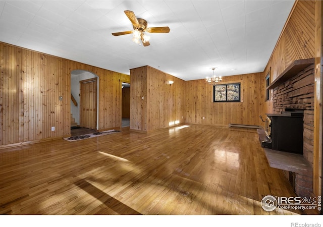 unfurnished living room featuring hardwood / wood-style floors, ceiling fan with notable chandelier, a fireplace, and baseboard heating