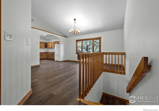 staircase with vaulted ceiling, hardwood / wood-style floors, and a notable chandelier