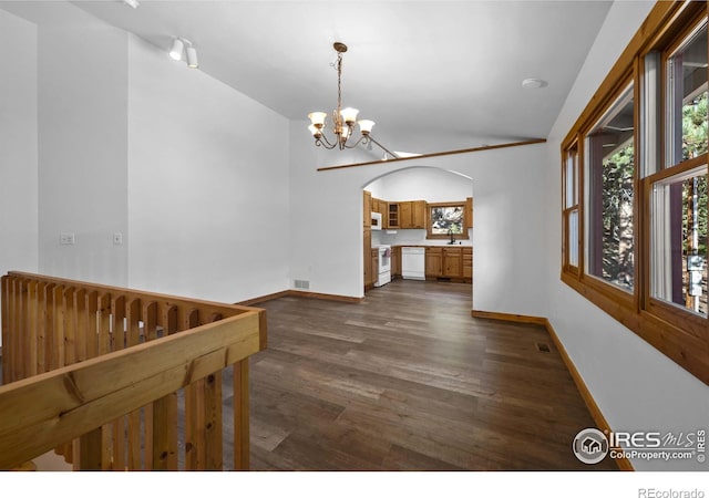 interior space with lofted ceiling, dark hardwood / wood-style floors, sink, and an inviting chandelier