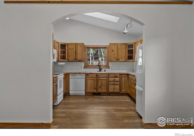 kitchen with vaulted ceiling, dark hardwood / wood-style floors, rail lighting, sink, and white appliances