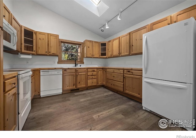 kitchen featuring dark wood-type flooring, rail lighting, sink, white appliances, and vaulted ceiling with skylight