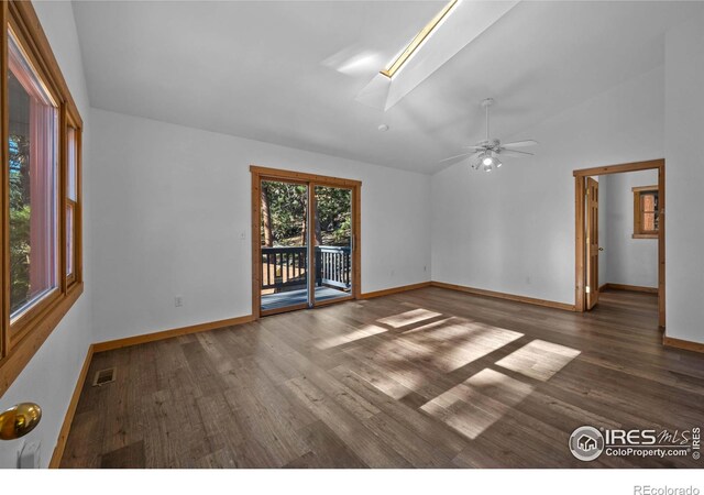 unfurnished room with dark hardwood / wood-style floors, vaulted ceiling with skylight, and ceiling fan