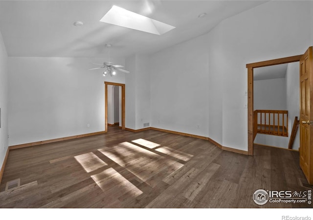 spare room featuring lofted ceiling with skylight, dark wood-type flooring, and ceiling fan