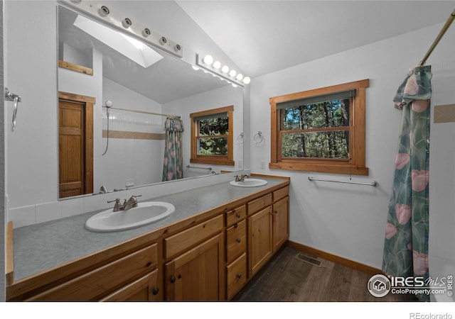 bathroom featuring vanity, hardwood / wood-style floors, curtained shower, and vaulted ceiling with skylight