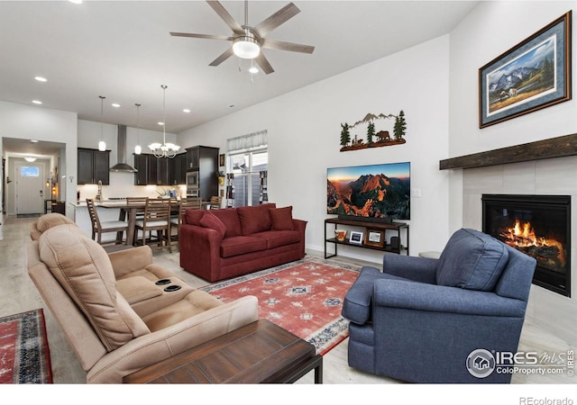 living room with ceiling fan with notable chandelier and a fireplace