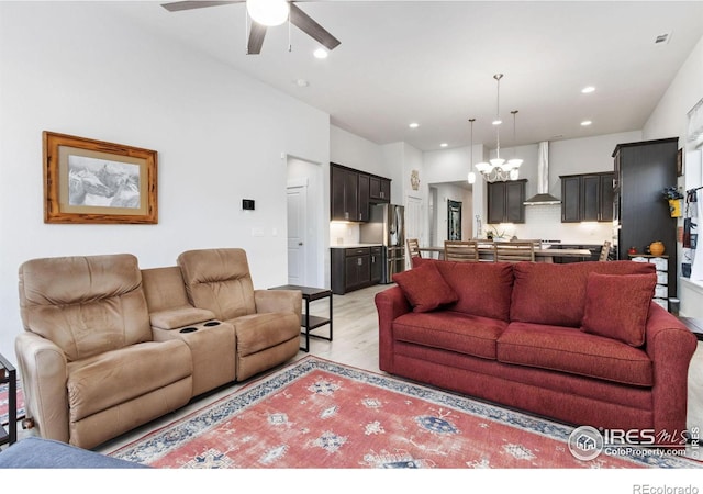 living room featuring ceiling fan with notable chandelier and light hardwood / wood-style flooring