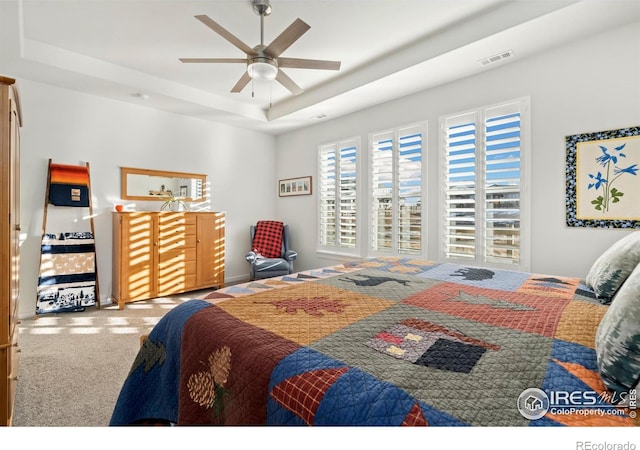 bedroom with ceiling fan, carpet flooring, and a raised ceiling