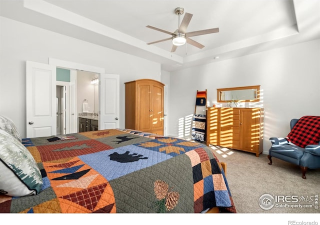 carpeted bedroom featuring connected bathroom, ceiling fan, and a tray ceiling