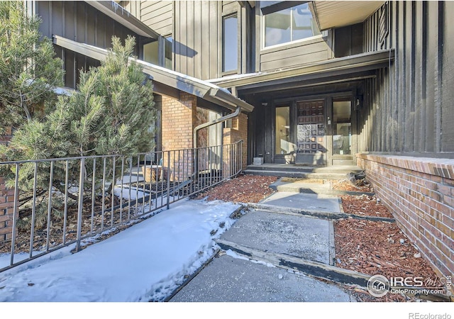 property entrance with fence, board and batten siding, and brick siding