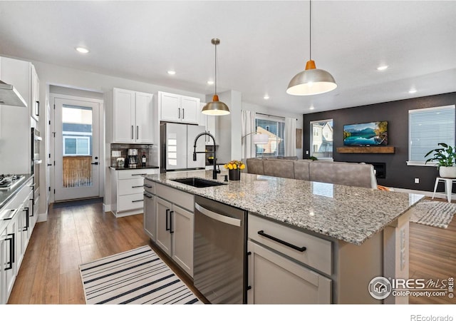 kitchen featuring sink, decorative light fixtures, a center island with sink, appliances with stainless steel finishes, and white cabinets