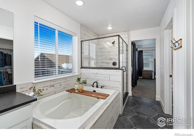 bathroom with plenty of natural light, independent shower and bath, tile patterned flooring, and vanity