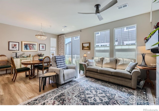 living room with hardwood / wood-style flooring and ceiling fan with notable chandelier