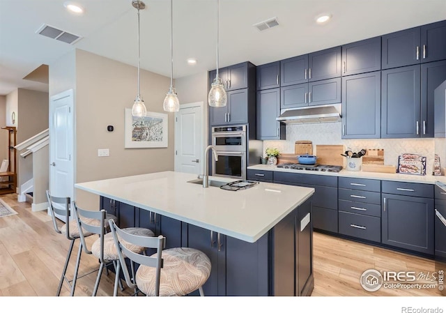 kitchen with blue cabinets, a kitchen island with sink, sink, and a kitchen bar