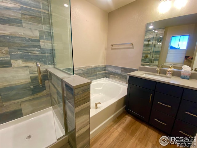 bathroom featuring wood-type flooring, vanity, and plus walk in shower