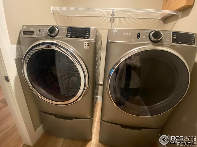 washroom with independent washer and dryer and light hardwood / wood-style flooring