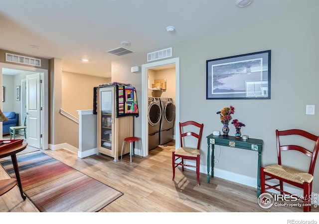 interior space with washing machine and dryer and light hardwood / wood-style flooring