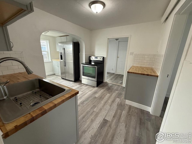 kitchen featuring butcher block counters, sink, backsplash, and appliances with stainless steel finishes