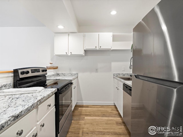 kitchen featuring light stone counters, stainless steel appliances, white cabinets, and light wood-type flooring