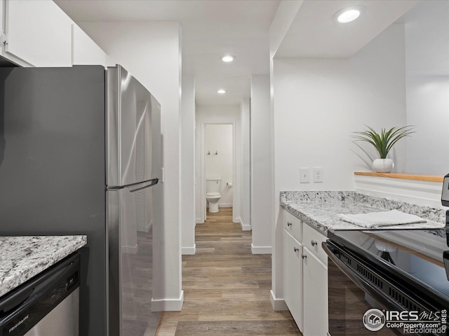 kitchen featuring light stone counters, stainless steel appliances, light hardwood / wood-style flooring, and white cabinets