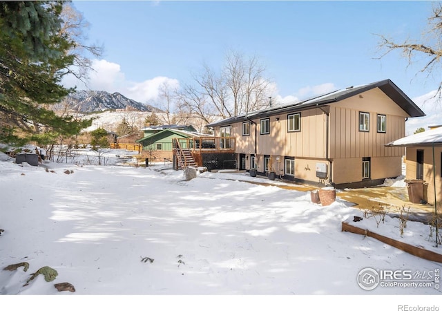 snow covered house with a deck with mountain view