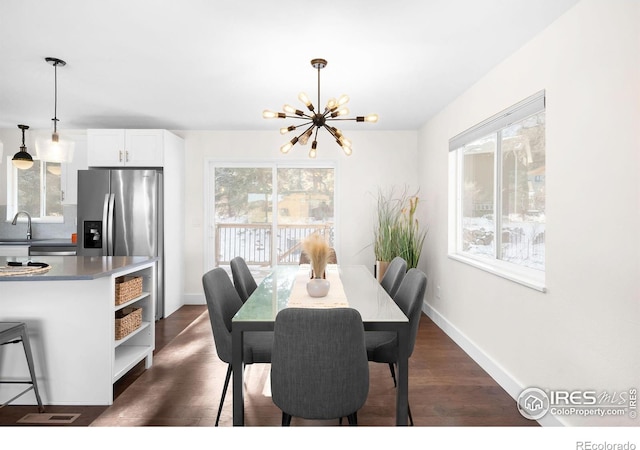 dining space with a notable chandelier, sink, and dark hardwood / wood-style floors