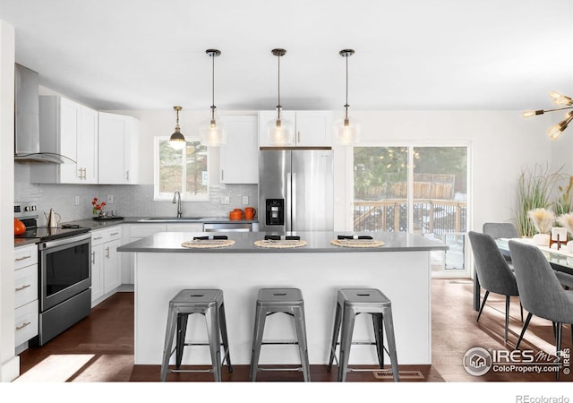 kitchen featuring sink, stainless steel appliances, a center island, and wall chimney exhaust hood