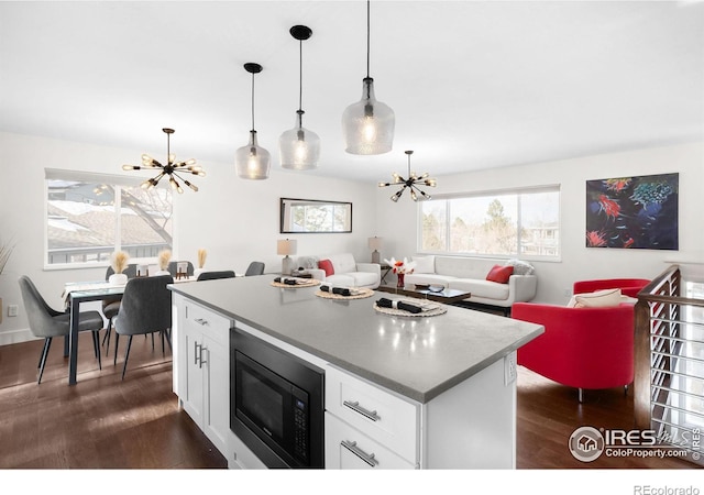 kitchen featuring a chandelier, hanging light fixtures, black microwave, and white cabinets