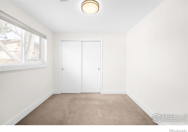 unfurnished bedroom with light carpet and a closet