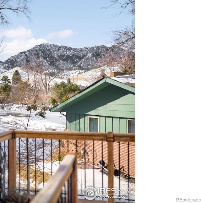 snow covered back of property featuring a mountain view