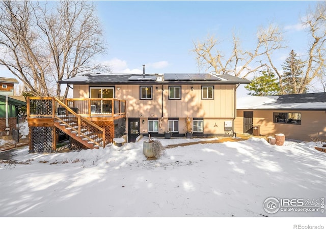 snow covered property with a deck and solar panels