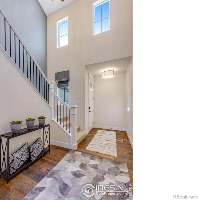 entrance foyer with hardwood / wood-style flooring and a towering ceiling