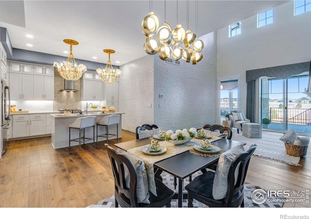 dining space featuring hardwood / wood-style flooring, a healthy amount of sunlight, a chandelier, and a high ceiling