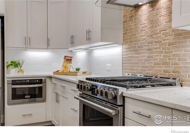 kitchen featuring white cabinetry, light stone countertops, appliances with stainless steel finishes, and tasteful backsplash