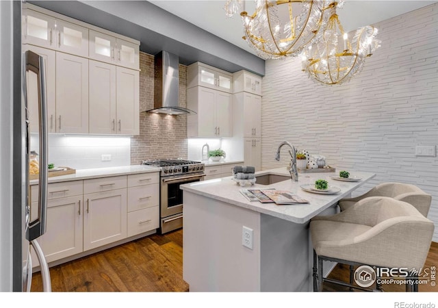 kitchen featuring pendant lighting, white cabinets, gas stove, a center island with sink, and wall chimney exhaust hood