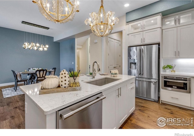 kitchen featuring an island with sink, stainless steel appliances, sink, and white cabinets