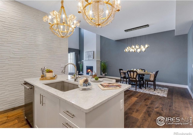 kitchen featuring pendant lighting, stainless steel dishwasher, sink, and an island with sink