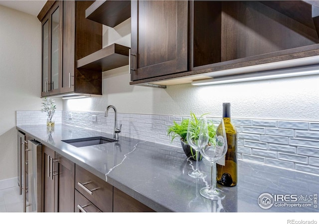 kitchen with light stone countertops, sink, and dark brown cabinets