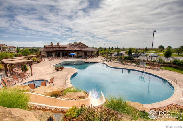 view of swimming pool with pool water feature and a patio area